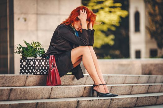 Worried business woman is crying in front of the office just after she got fired. 