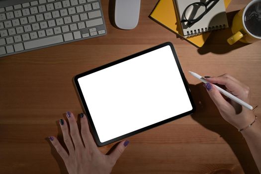 Creative woman hand holding stylus pen and using digital tablet on wooden desk.