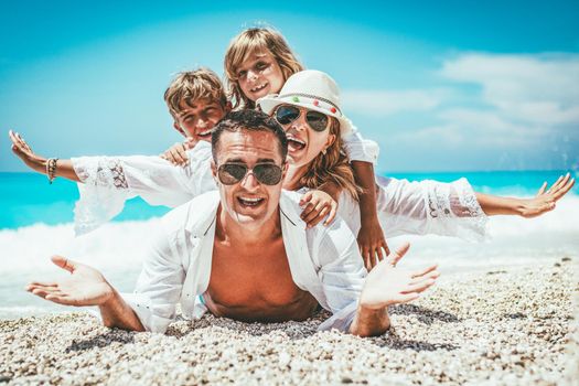 Happy young family with little kids having fun at the beach.