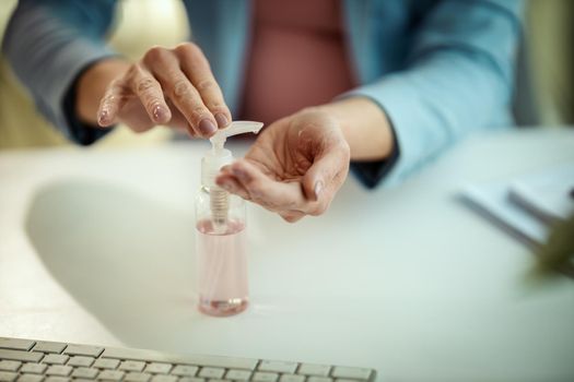 Close-up of a unrecognizable business woman uses antibacterial alcohol gel for hands disinfection in a works place during self-isolation and quarantine to avoid infection during flu virus outbreak and coronavirus epidemic.