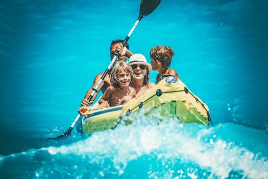 Happy family is enjoying paddling in yellow kayak at tropical ocean water during summer vacation.They are kayaking on the sea.