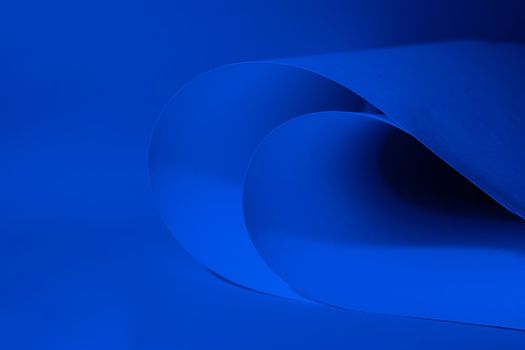 Abstract colored background, created with curved blue paper sheets. Curved lines and shapes and soft vivid colors.