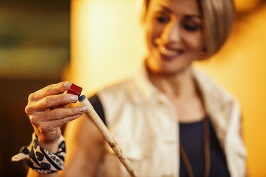 Smiling young woman apply chalk to the end of their cue sticks in billiard club. Selective focus, focus on chalk and stick.