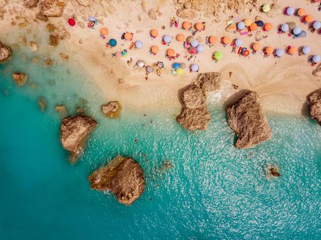 Aerial view of the amazing beach with colorful umbrella and people who relaxing and swimming in clear water of Mediterranean sea at sunny day.