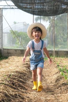 Little girl wearing a hat helps her mother in the garden, a little gardener. Cute girl playing in the vegetable garden.