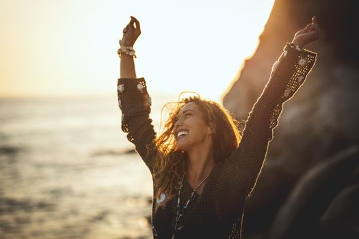 A beautiful young woman is having fun and relaxing on the beach at the sunset. 