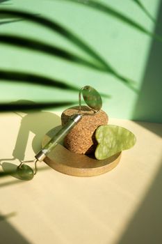 Jade Gua sha scraper and facial massager on beige background. Hard light, shadows, the concept self-care. Facial care. Zero waste. Lifting and toning treatment at home.