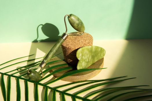 Jade Gua sha scraper and facial massager on beige background. Hard light, shadows, the concept self-care. Facial care. Zero waste. Lifting and toning treatment at home.