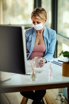 Business woman in a medical protective mask works from home at the computer during self-isolation and quarantine to avoid infection during flu virus outbreak and coronavirus epidemic.