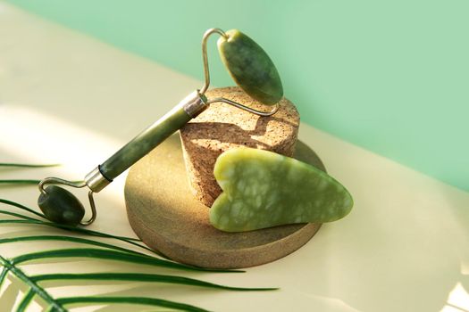 Jade Gua sha scraper and facial massager on beige background. Hard light, shadows, the concept self-care. Facial care. Zero waste. Lifting and toning treatment at home.