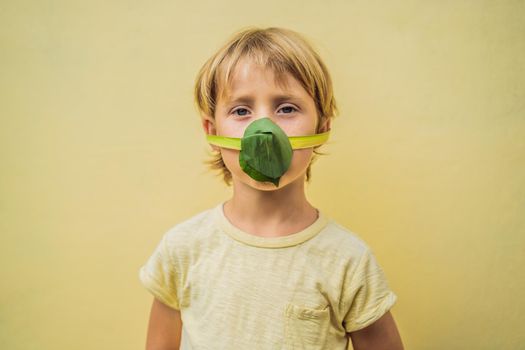 The child made himself a face mask from the leaves to protect himself from air pollution. Air purification for children concept. Trees purify the air concept.