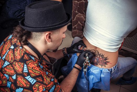 Skin master demonstrates the process of getting tattoo in tattoo parlour./Tattoo artist posing in tattoo studio.