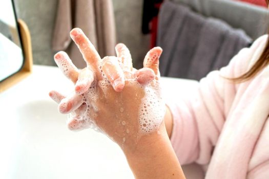 Little girl washing hands with water and soap in bathroom. Happy kid showing soapy palms. Hands hygiene and virus infections prevention. . High quality photo