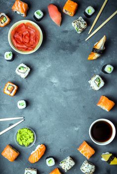 Japanese sushi on a dark background. Sushi rolls, nigiri, maki, pickled ginger, wasabi, soy sauce. Sushi set on a table. Space for text. Top view. Sushi background. Asian or Japanese food frame. Toned