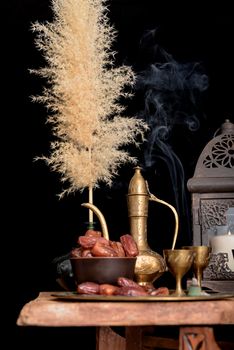 Ramadan Kareem Festive, close up of dates on wooden plate and rosary with oriental Lantern lamps and cup of black tea on wood background. Islamic Holy Month Greeting Card