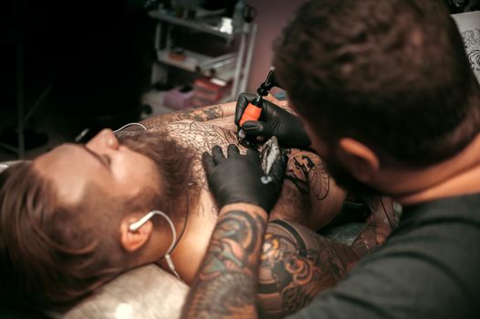 Tattooist works in tattoo studio.