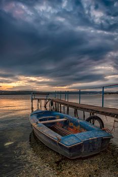 Beauty tranquil sunset on the harbor with a boat. Vertical view