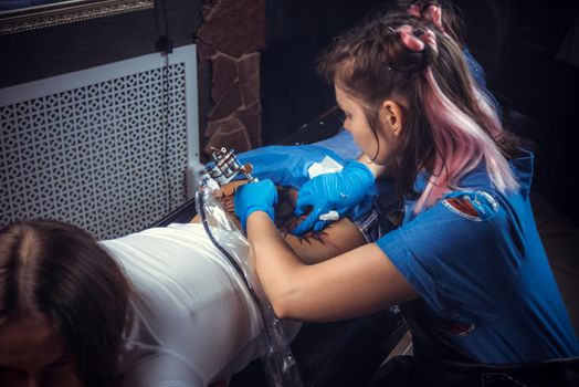 Master making a tattoo in tattoo parlour./Tattooist working on professional tattoo machine device in studio.