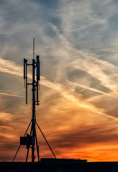 silhouette of GSM transmitters on the roof office building at amazing clouds