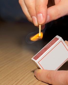 To light a match. The woman lights a match fire from a box of matches