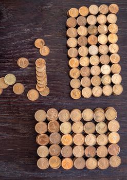 Many rows of stacked coins next to coins scattered on a table. Top view