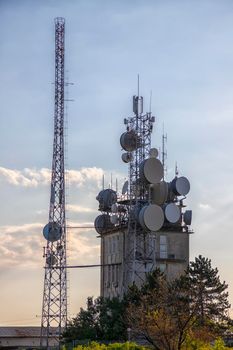 Mobile communication tower with control devices and antennas, transmitters, mobile communications, and the Internet at sunset