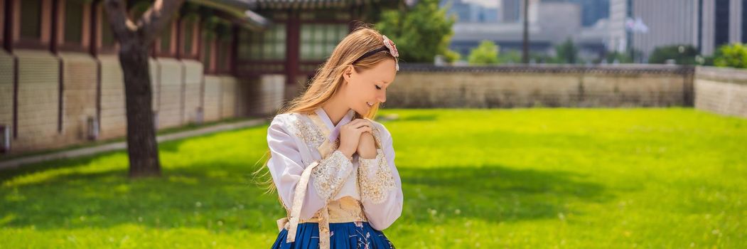 Young caucasian female tourist in hanbok national korean dress. Travel to Korea concept. National Korean clothing. Entertainment for tourists - trying on national Korean clothing. BANNER, LONG FORMAT