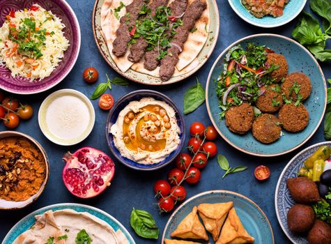 Middle eastern or arabic dishes and assorted meze, concrete rustic background. Meat kebab, falafel, baba ghanoush, muhammara, hummus, sambusak, rice, tahini, kibbeh, pita. Halal food. Lebanese cuisine