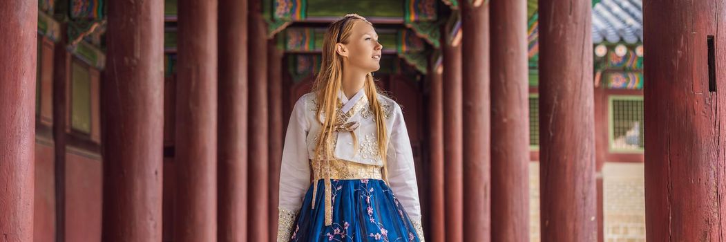 Young caucasian female tourist in hanbok national korean dress. Travel to Korea concept. National Korean clothing. Entertainment for tourists - trying on national Korean clothing. BANNER, LONG FORMAT