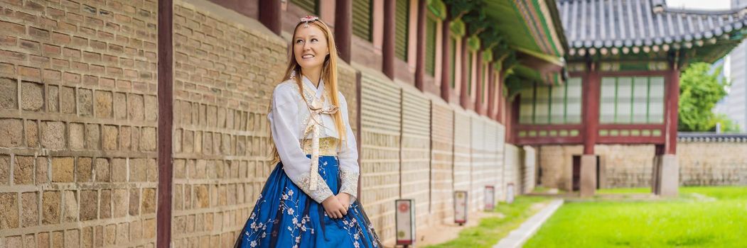 Young caucasian female tourist in hanbok national korean dress. Travel to Korea concept. National Korean clothing. Entertainment for tourists - trying on national Korean clothing. BANNER, LONG FORMAT