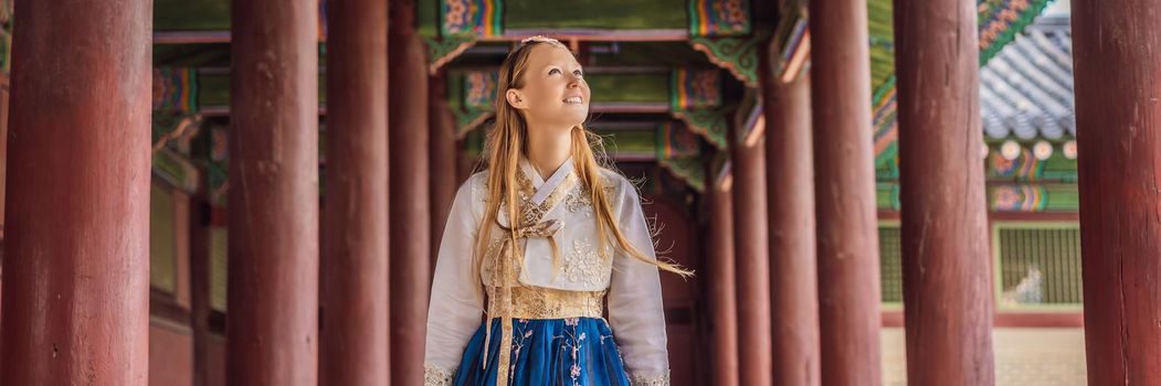 Young caucasian female tourist in hanbok national korean dress. Travel to Korea concept. National Korean clothing. Entertainment for tourists - trying on national Korean clothing. BANNER, LONG FORMAT