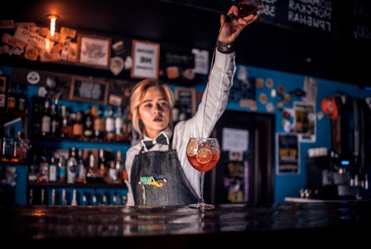 Girl barman mixes a cocktail in the alehouse