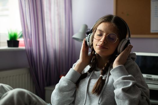 Listening to music on headphones. Young European girl. Teenage girl enthralled with new music. Closed eyes and hands on headphones.