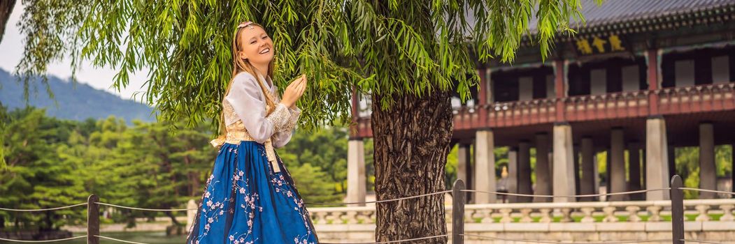 Young caucasian female tourist in hanbok national korean dress. Travel to Korea concept. National Korean clothing. Entertainment for tourists - trying on national Korean clothing. BANNER, LONG FORMAT