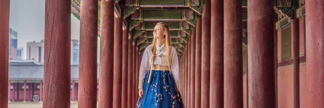 Young caucasian female tourist in hanbok national korean dress. Travel to Korea concept. National Korean clothing. Entertainment for tourists - trying on national Korean clothing. BANNER, LONG FORMAT