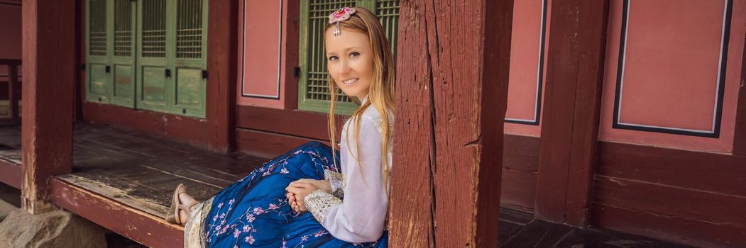 Young caucasian female tourist in hanbok national korean dress. Travel to Korea concept. National Korean clothing. Entertainment for tourists - trying on national Korean clothing. BANNER, LONG FORMAT