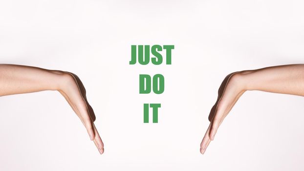 Motivational horizontal poster. Women's hands in a pointing gesture. Green motivating inscription 'Just Do It'. Palm Show Something. Copy Space.