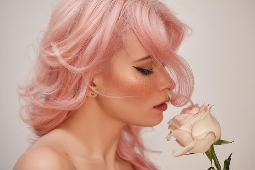 Soft-Girl Style with Trend Pink Flying Hair, Fashion Make-up. Woman Face with Fake Freckles and Rose Flowers. Blonde Female Model with perfect Fresh Clean Skin, Blush Rouge