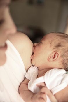 serene newborn baby in his mother's arms on the background of children's room