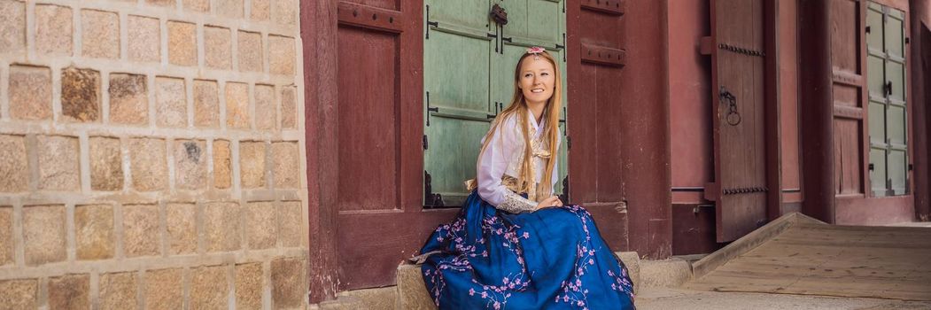 Young caucasian female tourist in hanbok national korean dress. Travel to Korea concept. National Korean clothing. Entertainment for tourists - trying on national Korean clothing. BANNER, LONG FORMAT