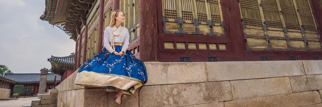 Young caucasian female tourist in hanbok national korean dress. Travel to Korea concept. National Korean clothing. Entertainment for tourists - trying on national Korean clothing. BANNER, LONG FORMAT