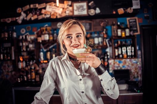 Girl barman creates a cocktail behind the bar