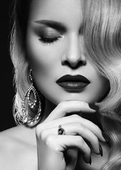 Portrait of beautiful young sexy woman with vintage make-up and blond hairstyle. Diva of cinematograph in black and white noir style. American diva style with shiny brilliants jewelry