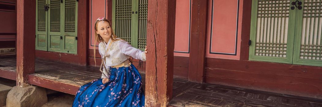 Young caucasian female tourist in hanbok national korean dress. Travel to Korea concept. National Korean clothing. Entertainment for tourists - trying on national Korean clothing. BANNER, LONG FORMAT