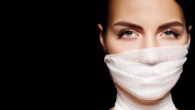 Beautiful woman with a bandage mask on face. Fashion eye make-up. Beauty plastic surgery or protection hygiene in viral covid-19 pandemic
