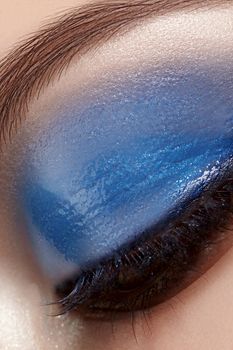 Closeup Macro of Woman Face with Blue Eyes Make-up. Fashion Celebrate Makeup, Glowy Wet Eye Shadows and Black Eyelashes. Perfect Beauty Cosmetics with Gloss Makeup