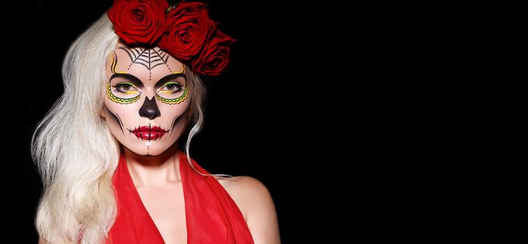 Beautiful Halloween Make-Up Style. Blond Model Wear Sugar Skull Makeup with Red Roses, pale Skin Tones and Waves Hair. Santa Muerte concept