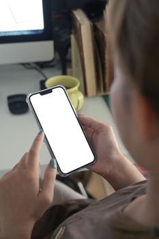 Over shoulder view of female worker using smart phone at her workplace.