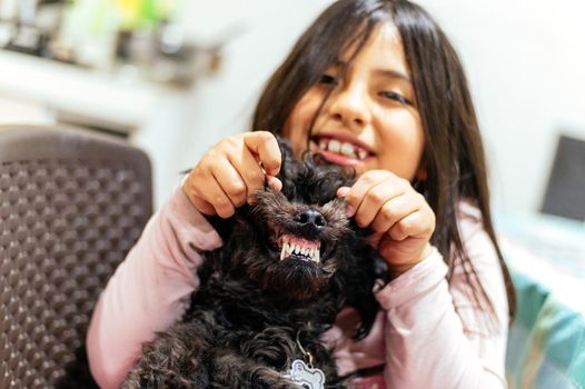 Adorable smiling little girl child schoolgirl holding and playing with pet dog. Best friends