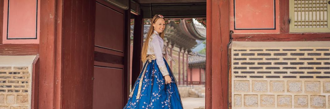 Young caucasian female tourist in hanbok national korean dress. Travel to Korea concept. National Korean clothing. Entertainment for tourists - trying on national Korean clothing. BANNER, LONG FORMAT